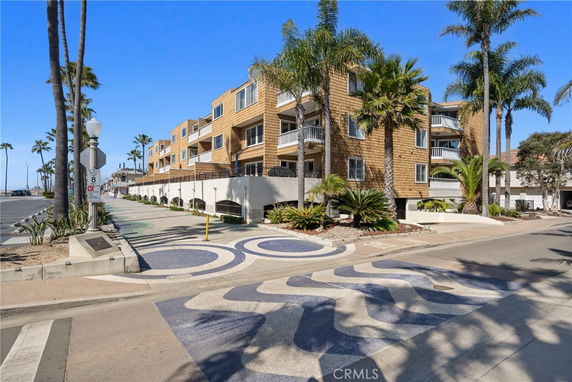Front view of a multi-story building with balconies and palm trees.