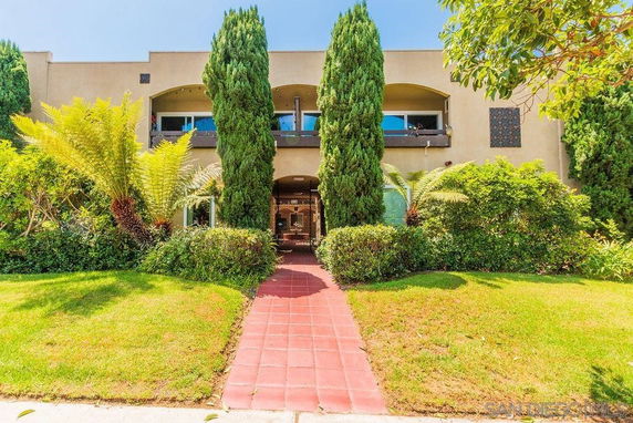 Front view of a two-story building with a central entrance and surrounding greenery.