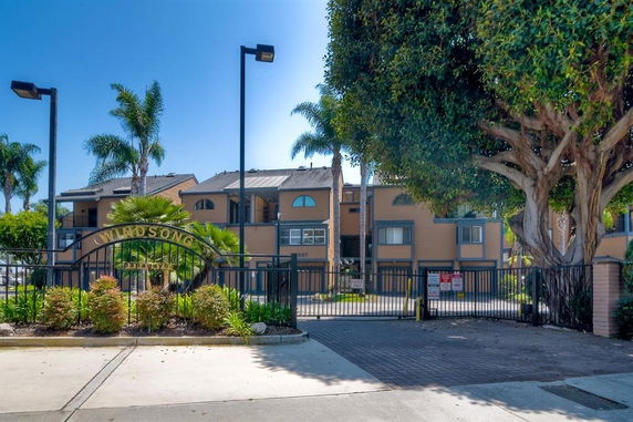 Front view of a multi-story residential building with a gated entrance.