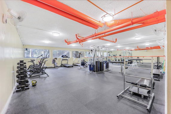 Interior view of a gym with exercise equipment and mirrors.