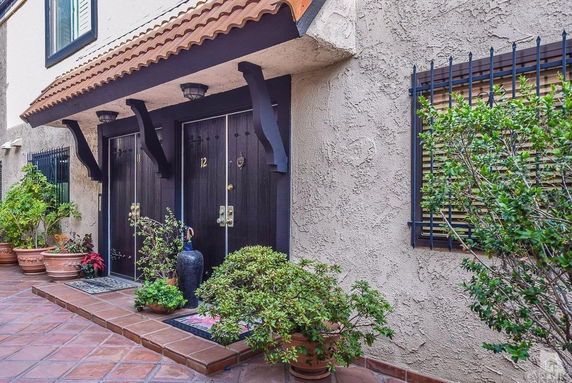 Front view of a house entrance with double doors and potted plants.