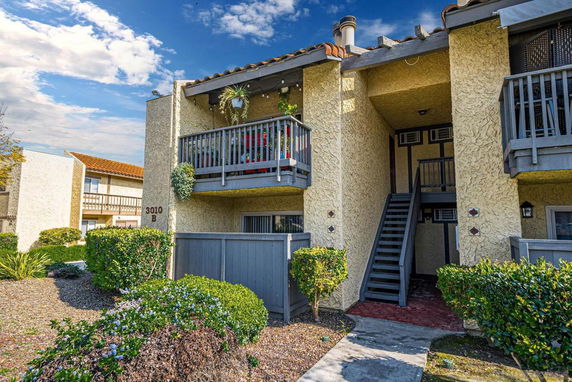 Front view of a two-story residential building with balconies and stairs.
