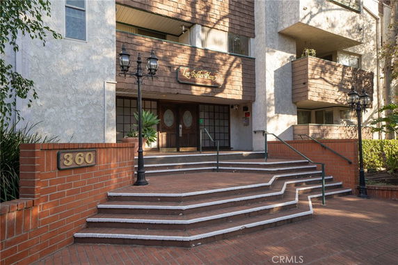 Front view of a building entrance with stairs and brick walls.