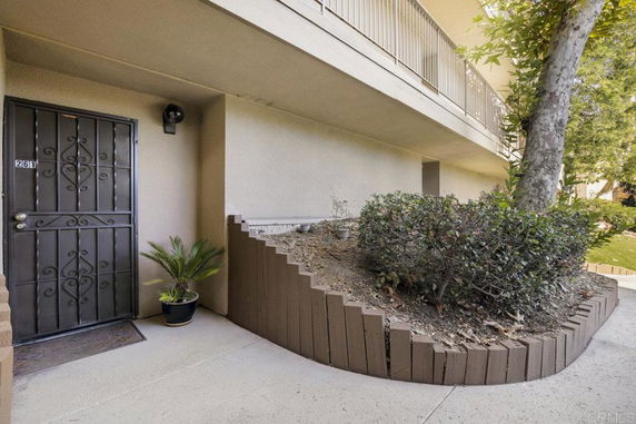 Front view of a building entrance with a metal door and a landscaped area.