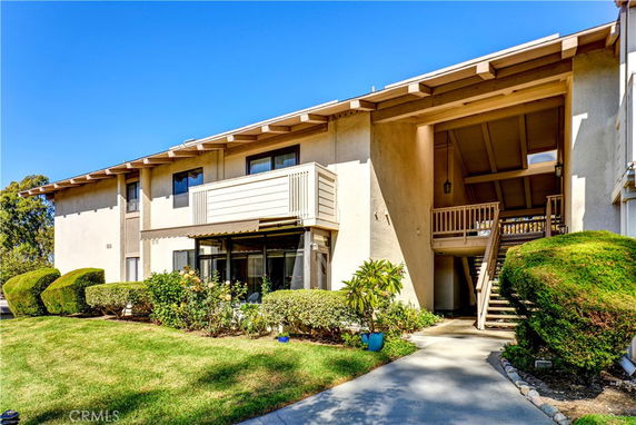 Front view of a two-story residential building with beige exterior and a staircase leading to the upper level.