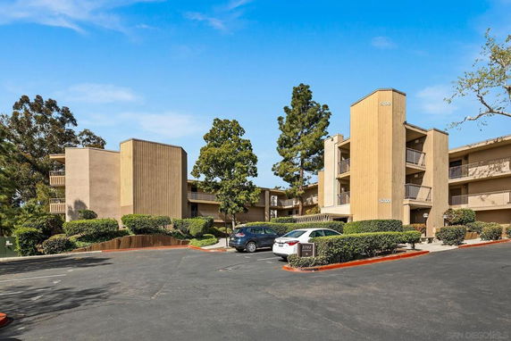Front view of a multi-story apartment building with parking area.