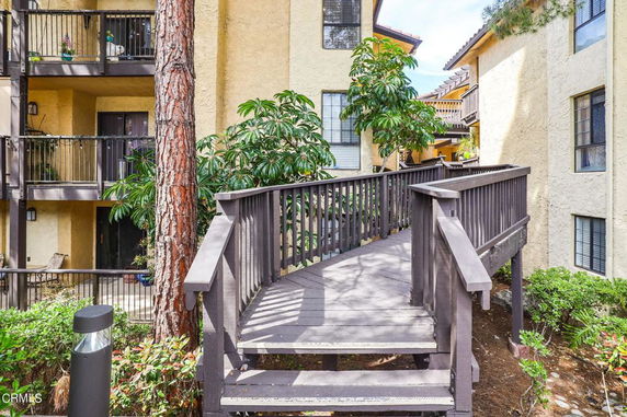 Front view of a multi-story residential building with balconies and a wooden ramp.