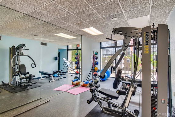 Indoor gym with exercise equipment and mirrors on the wall.
