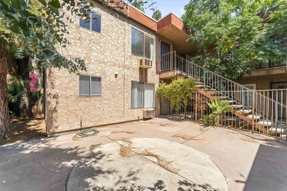 Exterior view of a two-story building with a stone facade and an outdoor staircase.