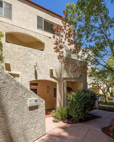 Front view of a multi-story building with textured walls and arched entrances.