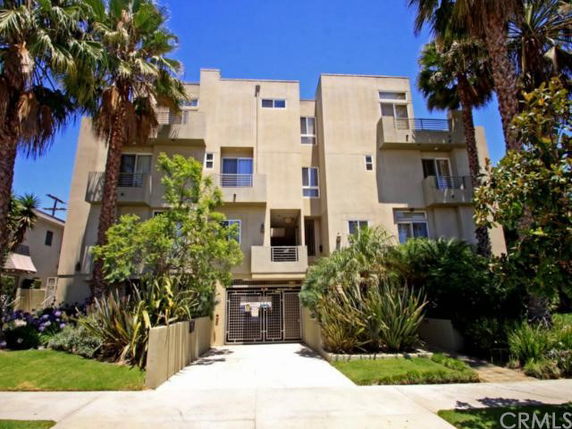 Front view of a multi-story residential building with balconies and gated entrance.