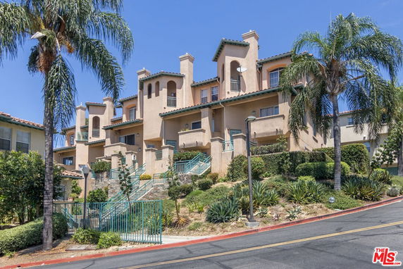 Front view of a multi-story residential building with balconies and a staircase entrance.