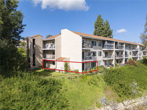 Front view of a multi-story apartment building with balconies and a red tile roof.