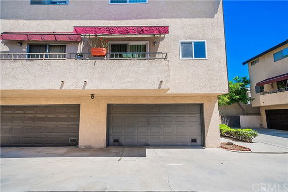 Front view of a multi-story building with two garage doors and a balcony.