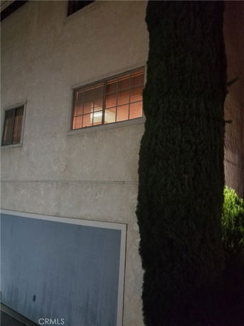 Front view of a building with two windows and a tree adjacent to it.