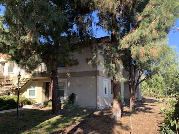 Exterior view of a two-story residential building with trees in front.