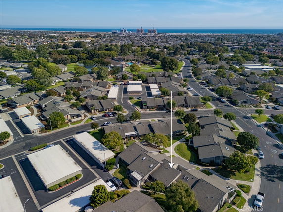 Panoramic aerial view of a residential area with multiple houses and distant sea.