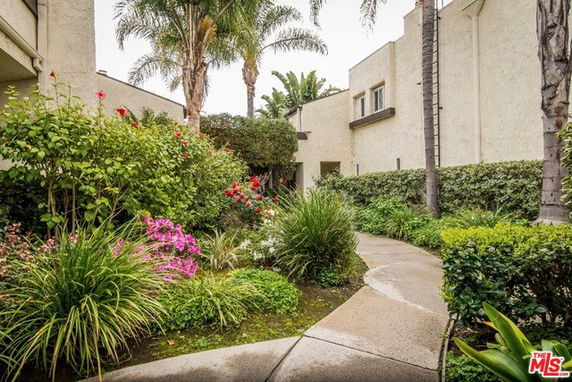 Exterior view of a building with pathway and lush greenery.