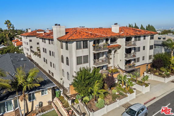 Front view of a multi-story apartment building with balconies and red tiled roof.
