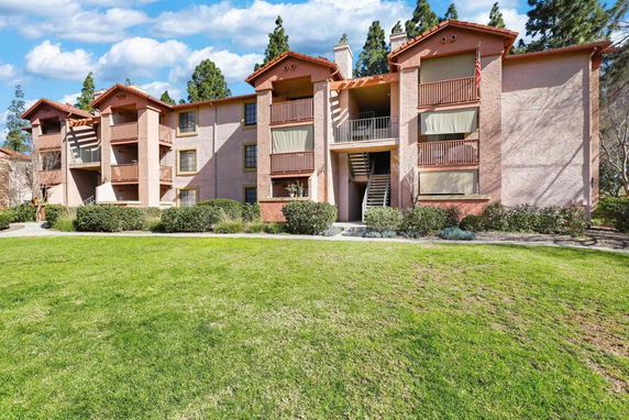 Front view of a multi-story residential building with balconies and staircases.