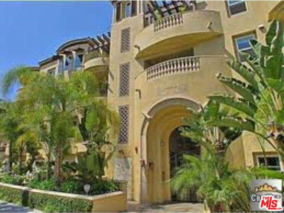 Front view of a multi-story building with balconies and archway entrance.