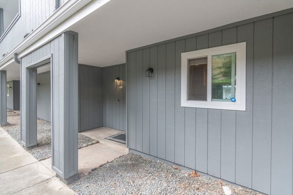 Front view of a house with a covered entryway and gray vertical siding.