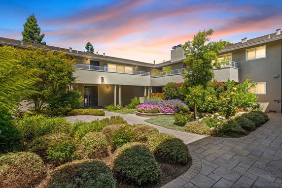 Front view of a multi-story house with balconies and landscaped garden.