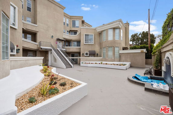Front view of a multi-story building with stairs and landscaped planters.