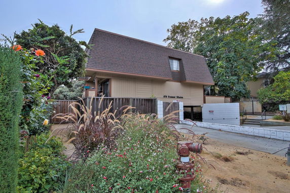 Front view of a multi-story house with a sloped roof and wooden exterior.