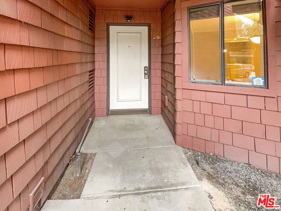 Front view of an entryway with a white door and red shingle siding.