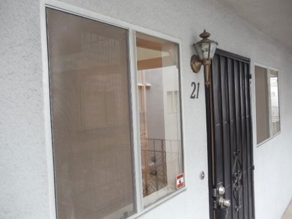 Side view of a building entrance with a metal security door and a wall-mounted lamp.