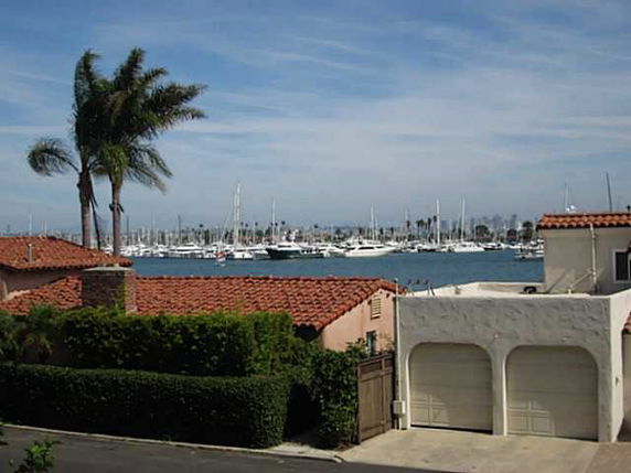 View of a marina with boats and palm trees, seen from a building.