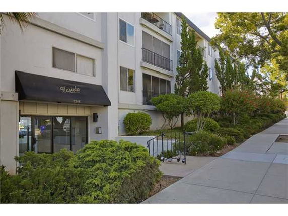 Front view of a multi-story apartment building with balconies and entrance canopy.