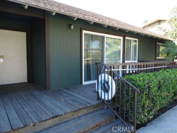 Front view of a house with a wooden deck and sliding glass doors.