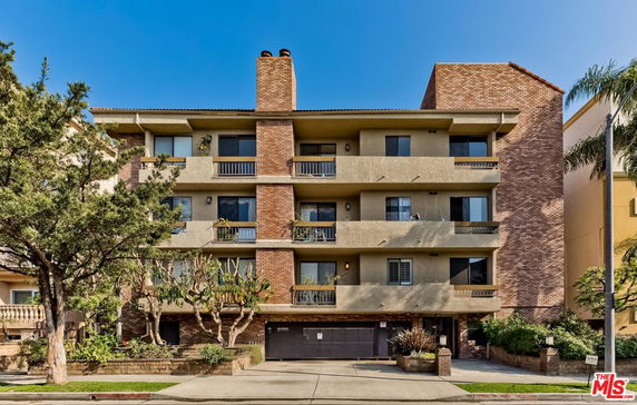 Front view of a multi-story residential building with balconies and brick elements.