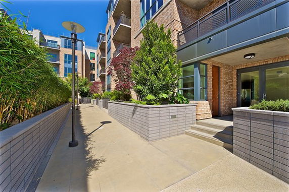 Front view of a modern multi-story building with balconies and large windows.