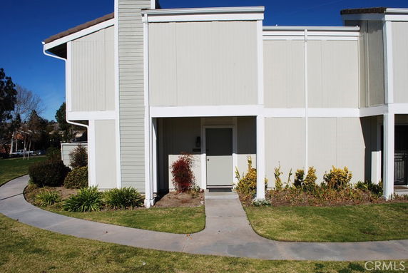 Front view of a two-story building with a beige exterior and a pathway leading to the entrance.