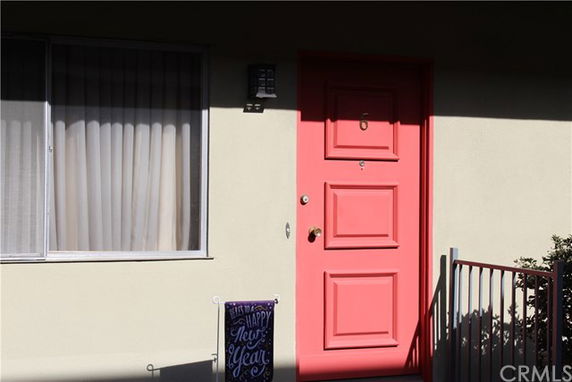 Front view of a house door with a pink color and a window on the left.
