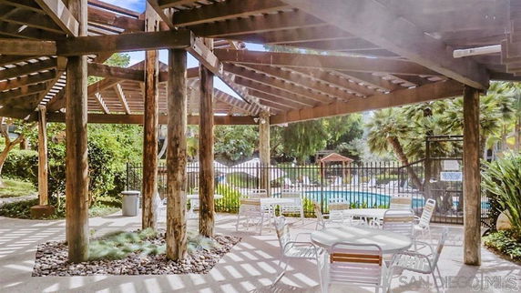 Outdoor area with a pergola and view of a swimming pool.