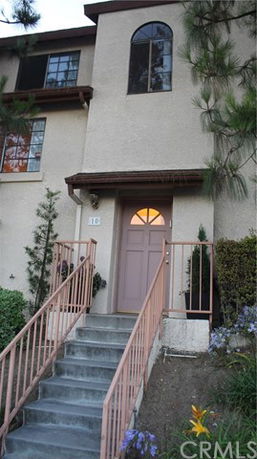 Front view of a multi-story house with stairs and entrance door.