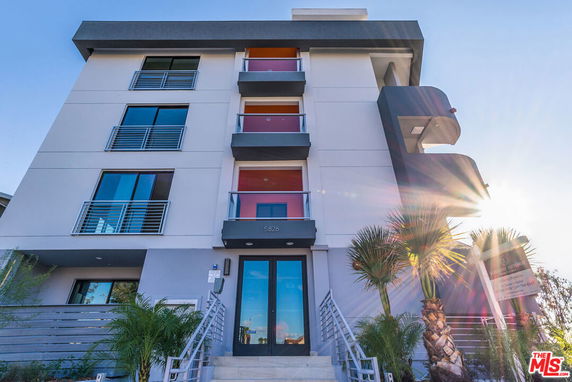 Front view of a modern multi-story building with balconies and glass doors.