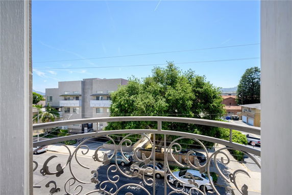 View from a building overlooking other buildings and trees on a sunny day.