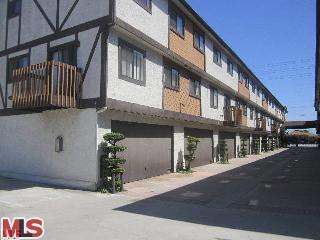 Front view of a multi-story residential building with a mix of stucco and wood paneling.