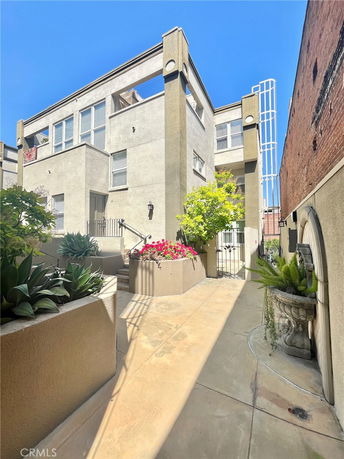 Front view of a multi-story residential building with a modern design and outdoor planters.