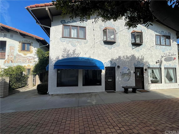 Front view of a two-story building with decorative windows and blue awnings.