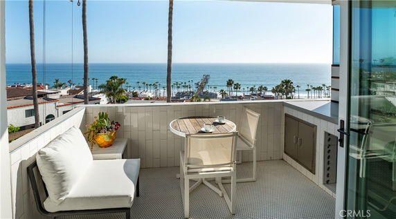 View from a balcony showing an ocean landscape with palm trees and a pier.
