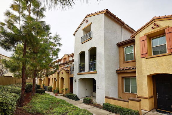 Front view of a multi-story residential building with balconies and brown shutters.