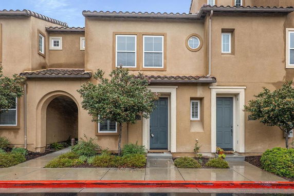 Front view of a two-story house with an archway entrance and two doors.