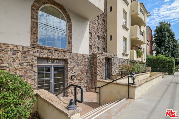 Front view of a multi-story building with stone facade and arched window.