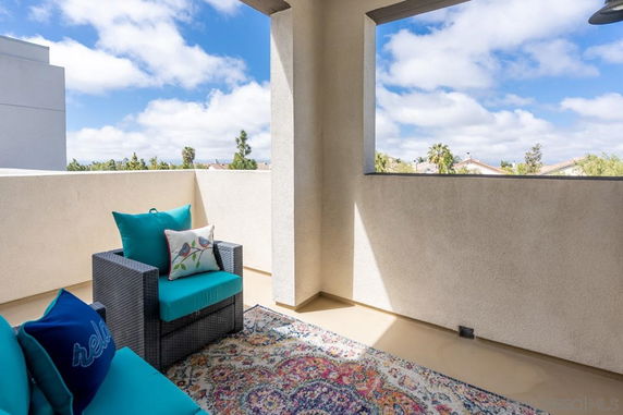 Balcony with outdoor seating offering a partial view of surrounding area and sky.